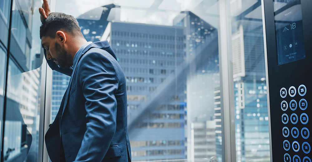 business executive stressed out in glass elevator